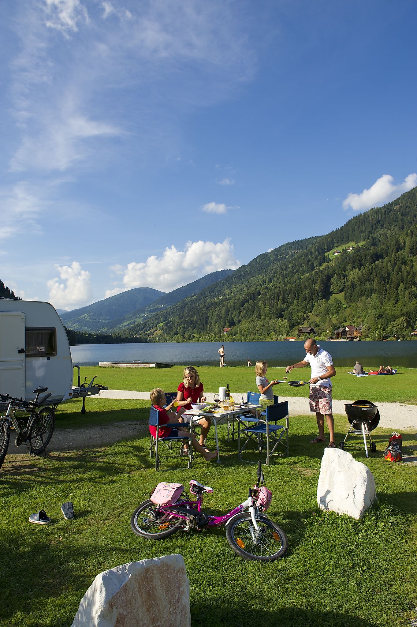 Eine Familie die am Campingplatz einen schönen sonnigen Tag verbringt und eine Grillerei macht.